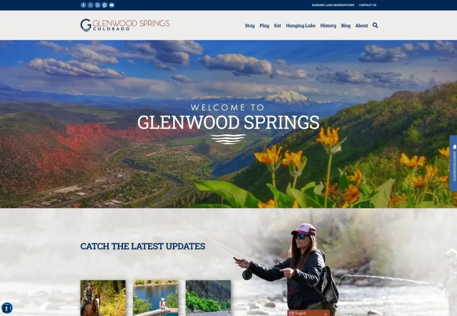 Screenshot of the Glenwood Springs, Colorado tourism website featuring a scenic mountain view with wildflowers, a welcome message, and an image of a woman fly fishing. Navigation menus are visible at the top.